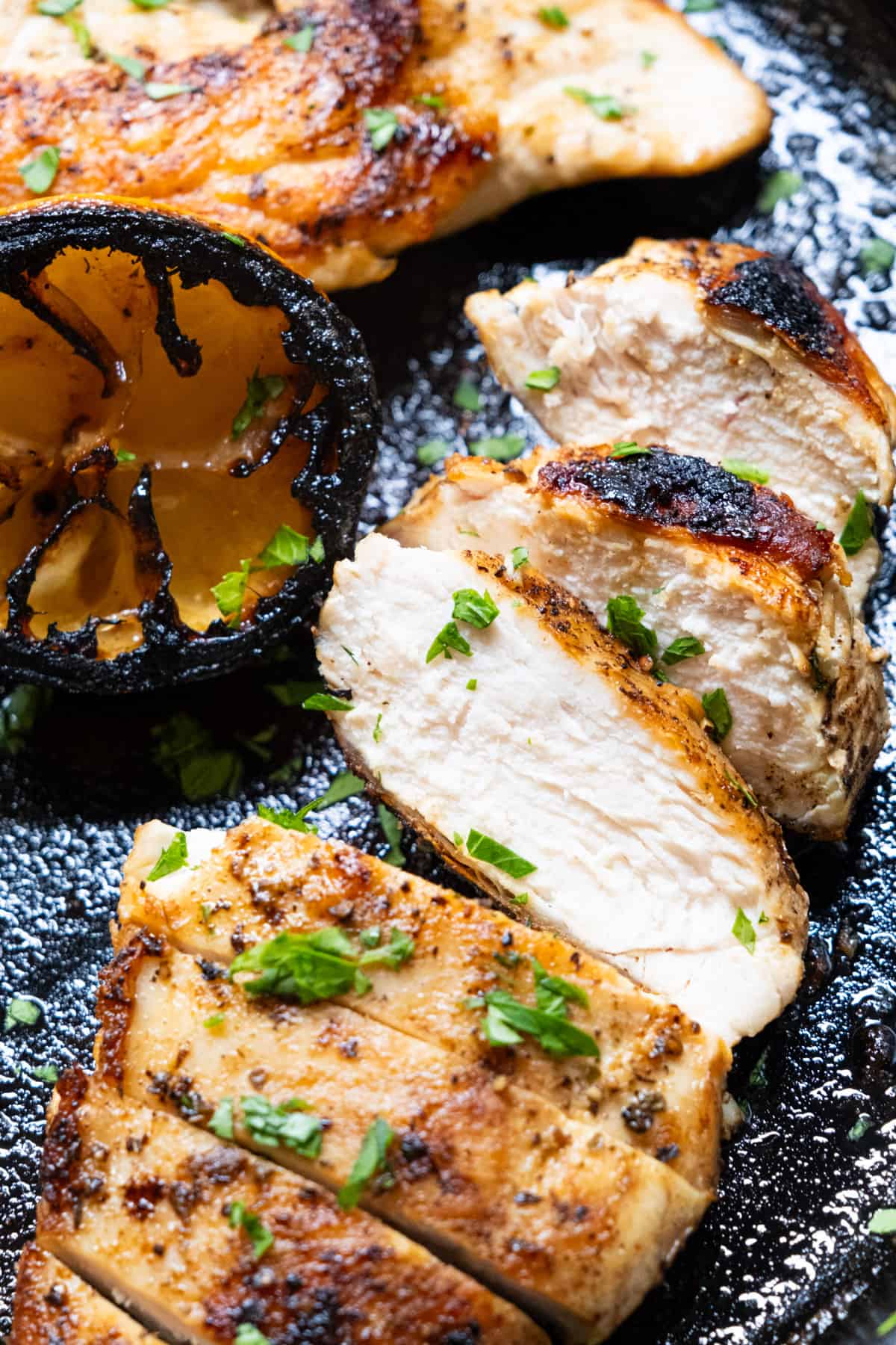 the perfectly juicy cast iron chicken breast sliced and laid on the cast iron