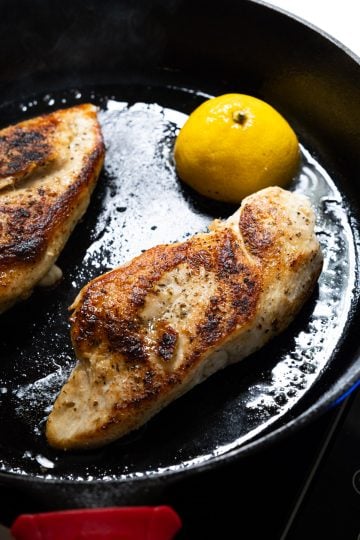 chicken flipped over in cast iron with lemon