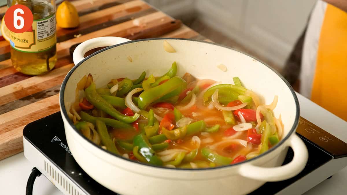 Simmering peppers and onions in white wine and vinegar.