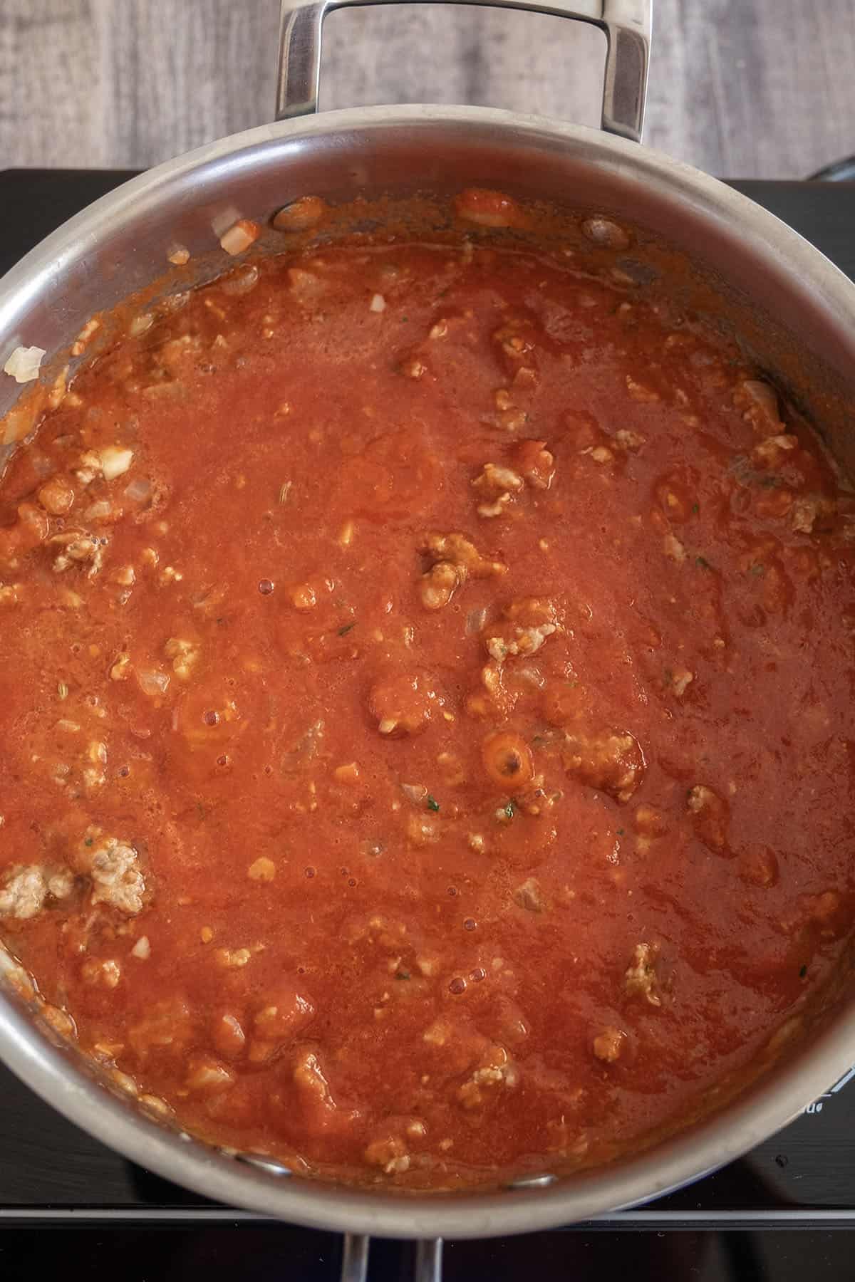 red sauce added to sausage and onions