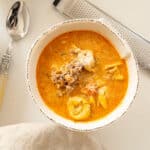 Rustic Italian tortellini soup with sausage in a bowl topped with parmesan cheese.