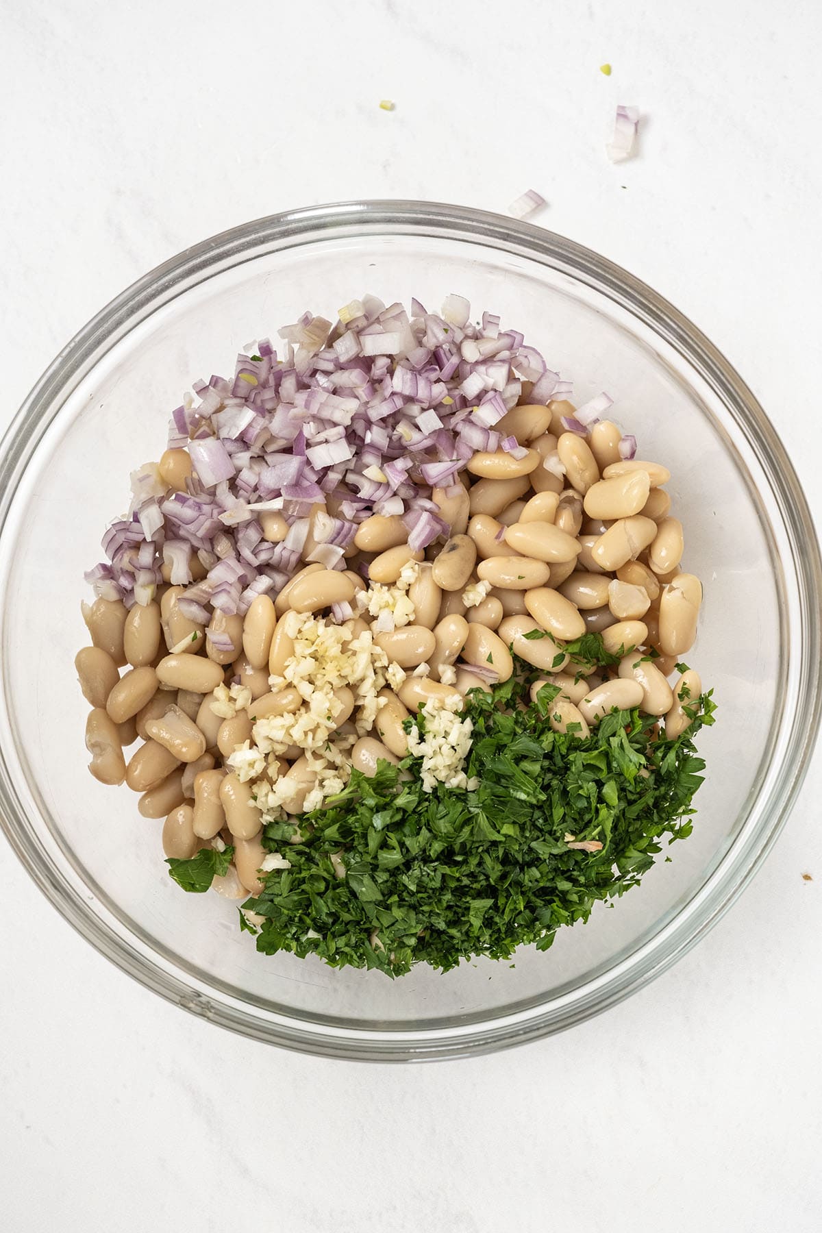 Vibrant Summer Farro & Cannellini Bean Salad 4 Cannellini beans, minced shallots, fresh parsley, and garlic combined in a bowl.