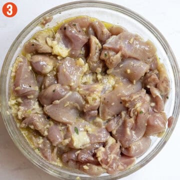 Marinating chopped chicken thighs in a bowl.