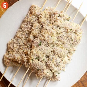 Breaded chicken skewers on a plate.