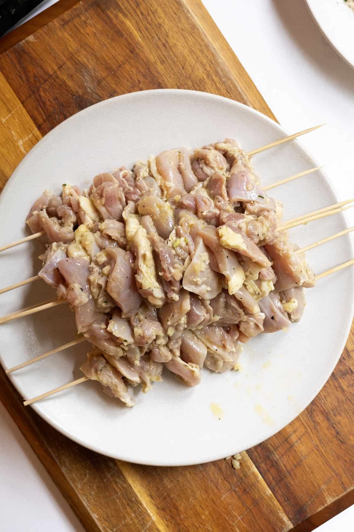 Grilled Chicken Skewers 8 Marinated chicken thighs being threaded onto wooden skewers.