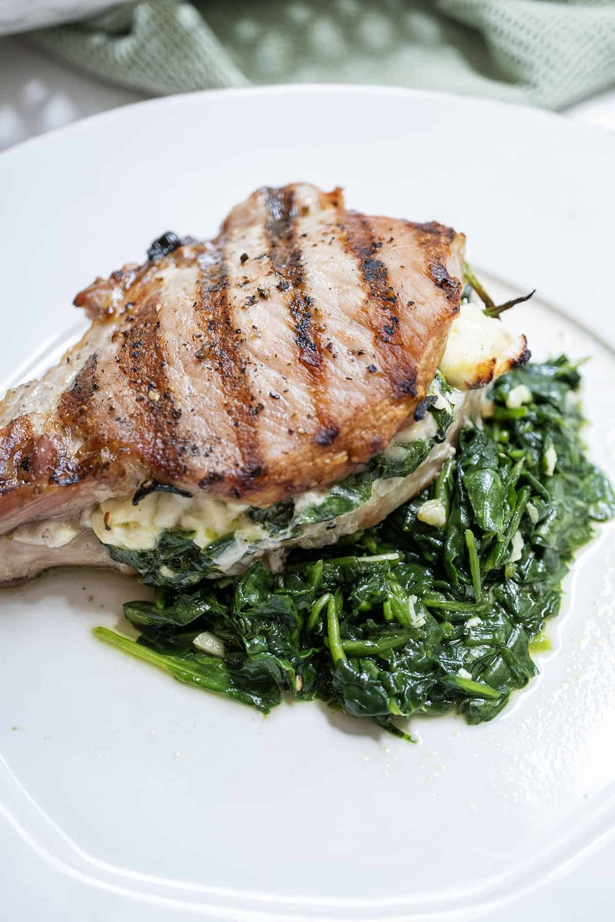 A grilled pork chop stuffed with feta and sauteed spinach and garlic served on more sauteed spinach.