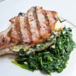 A grilled pork chop stuffed with feta and sauteed spinach and garlic served on more sauteed spinach.