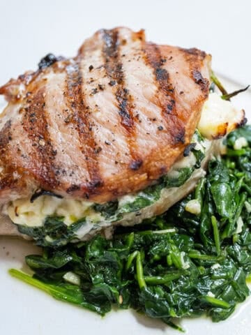 A grilled pork chop stuffed with feta and sauteed spinach and garlic served on more sauteed spinach.