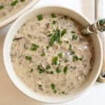 Creamy mushroom soup in a cup with a spoon.
