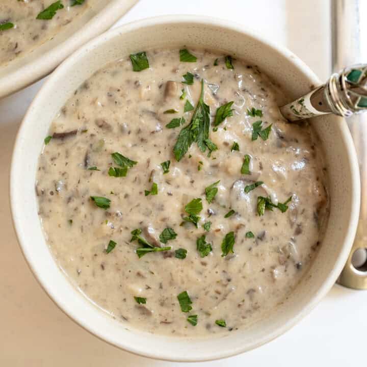 Creamy mushroom soup in a cup with a spoon.