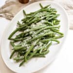 Sauteed green beans with garlic sprinkled with parmesan on a plate.