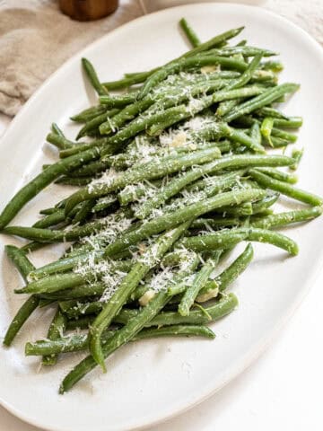 Sauteed green beans with garlic sprinkled with parmesan on a plate.