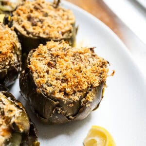 Stuffed artichokes on a plate with lemon.