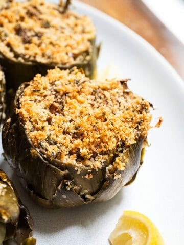 Stuffed artichokes on a plate with lemon.