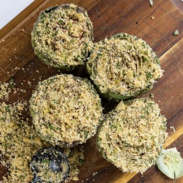 Artichokes on a cutting board stuffed with breadcrumbs and parmesan.