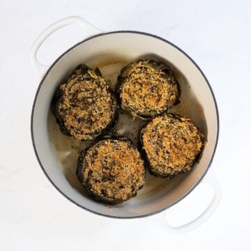 Steamed and broiled stuffed artichokes in a dutch oven.