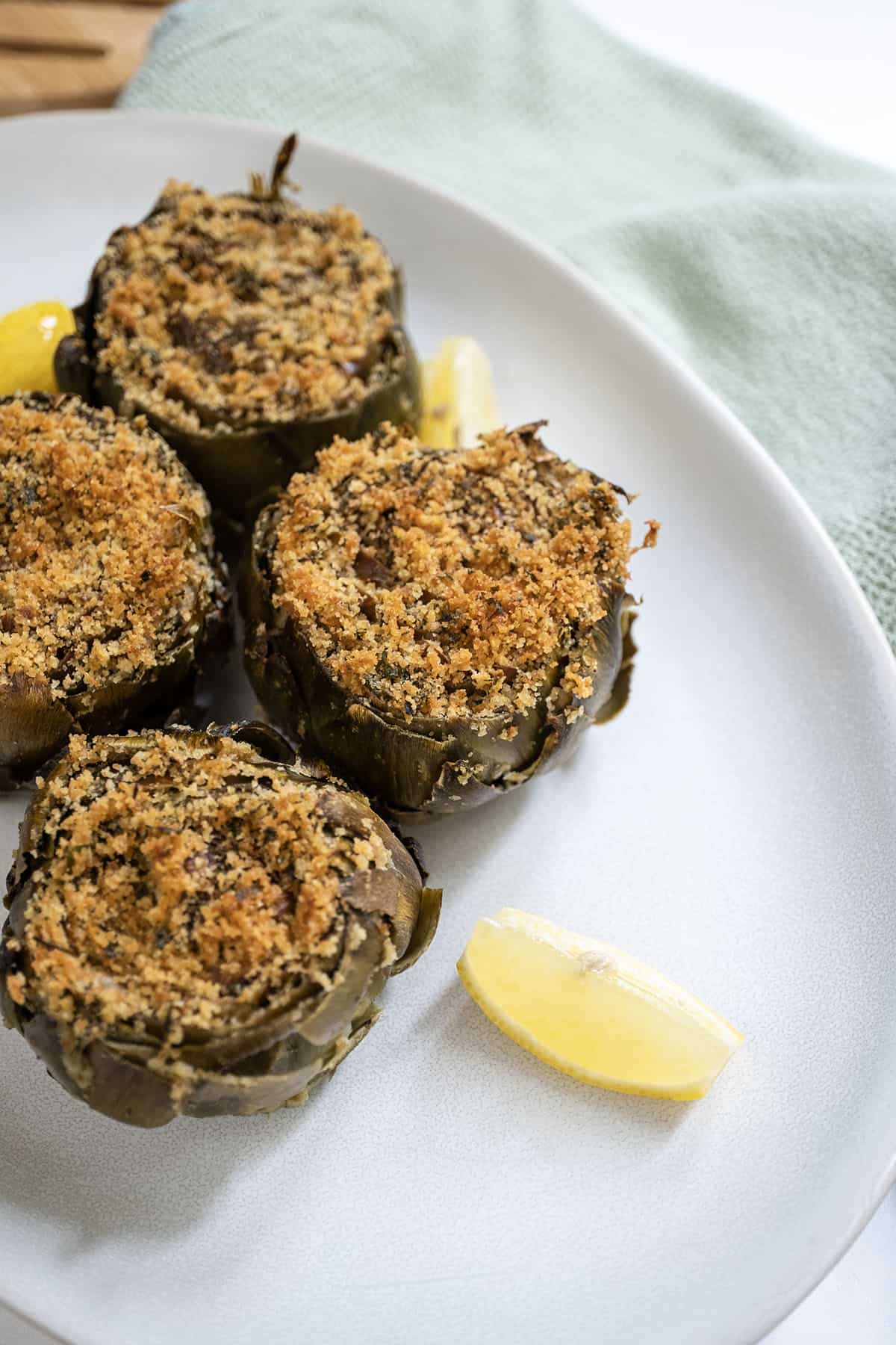 Stuffed artichokes on a plate with lemon.