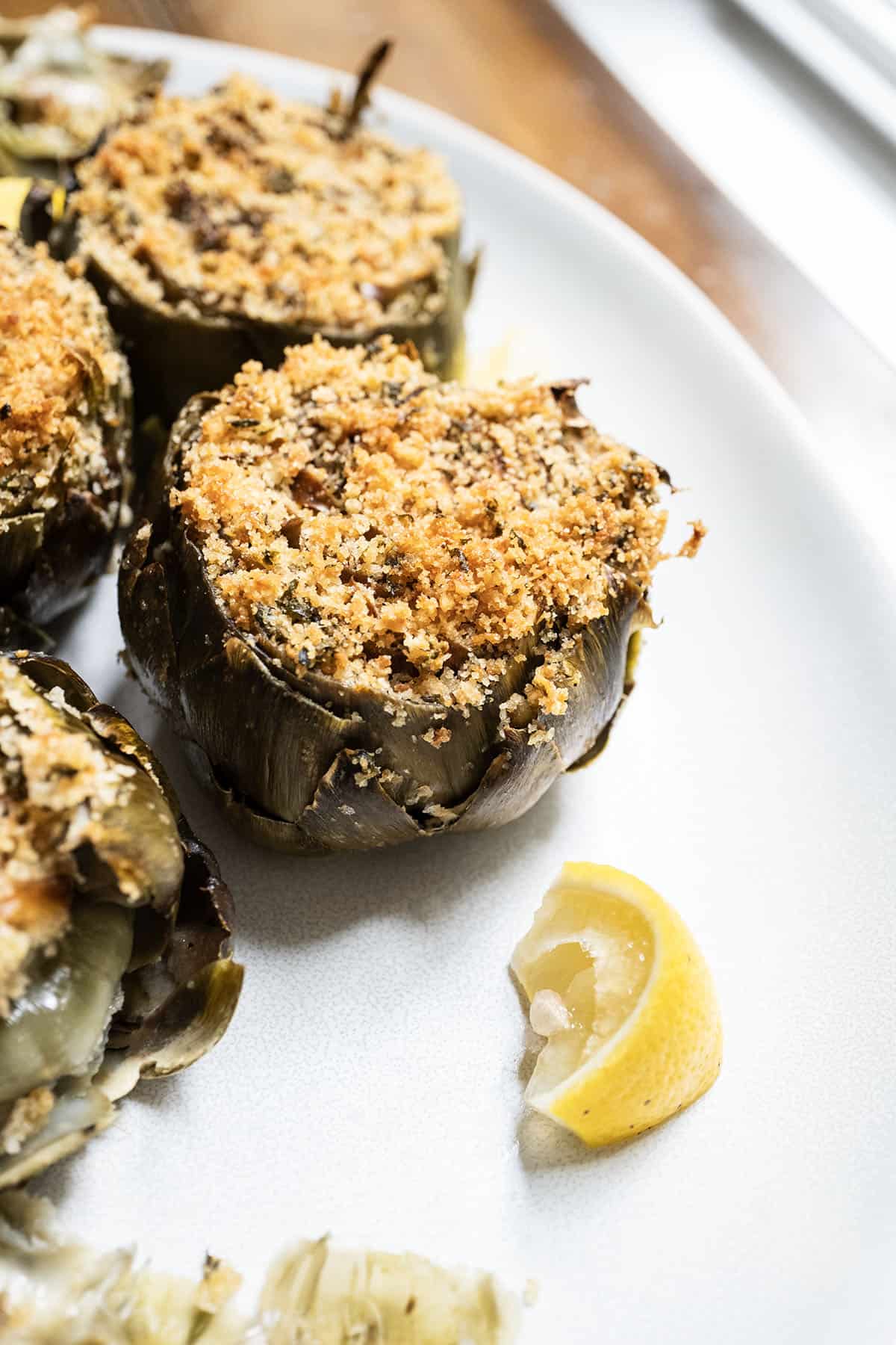 Stuffed artichokes on a plate with lemon.