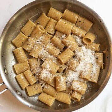 Pecorino romano added to the pan to continue tossing.