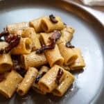 Pasta alla gricia served on a plate and topped with guanciale.