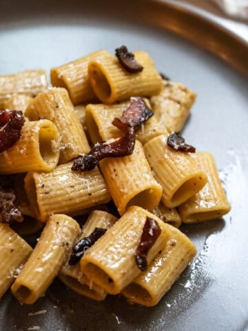 Pasta alla gricia served on a plate and topped with guanciale.