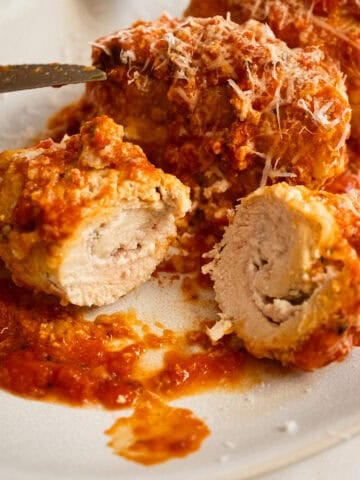 Chicken rollatini cut open with ricotta filling inside.