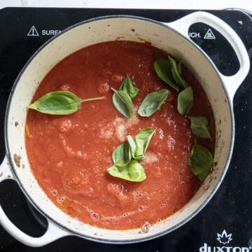 Simmering sauce topped with basil.