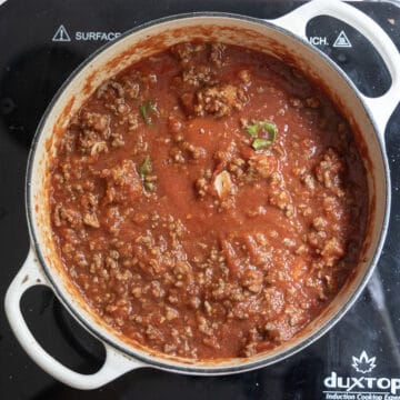 Meat added back to the dutch oven simmering with sauce.