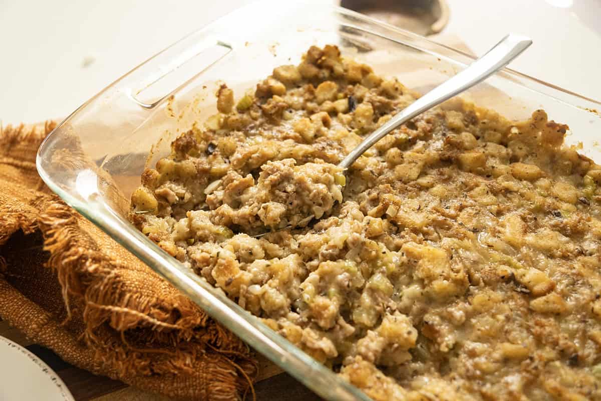 Thanksgiving stuffing cooked in a baking tray with a spoonful removed.