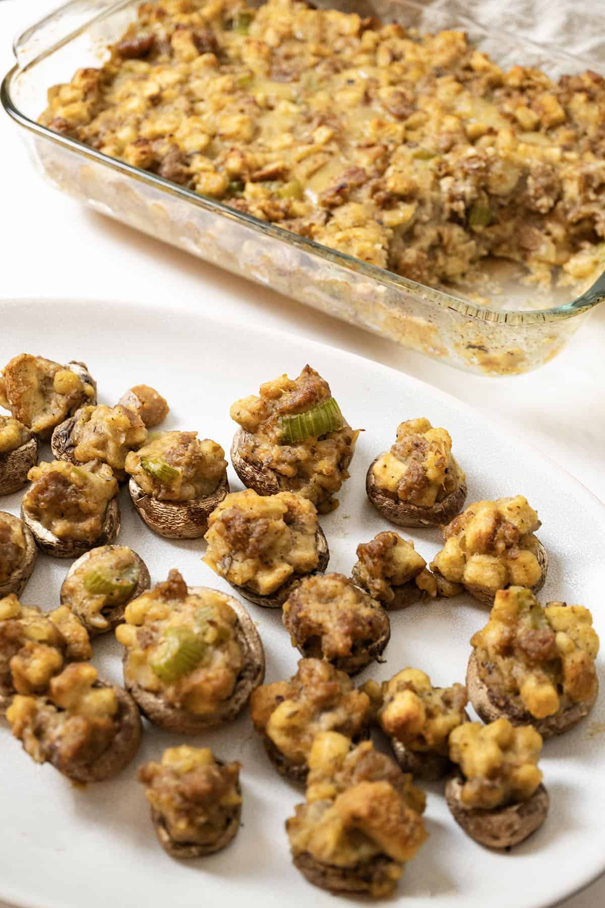 Italian sausage stuffing baked in a glass baking pan with stuffed mushrooms.