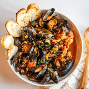 Mussels Fra Diavolo in a serving bowl with crostini.