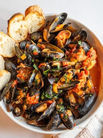 Mussels Fra Diavolo in a serving bowl with crostini.