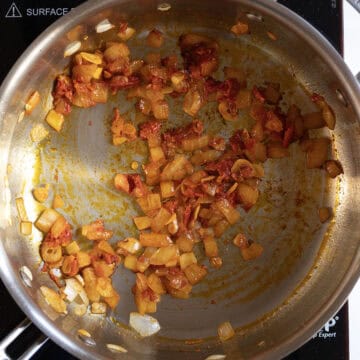 Onions sauteing with garlic, tomato paste, and calabrian chili peppers in a pan.