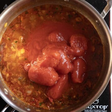 Whole plum tomatoes added to the wine filled pan.