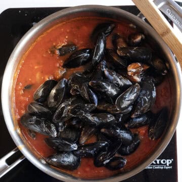 Mussels in tomato sauce in a pan.