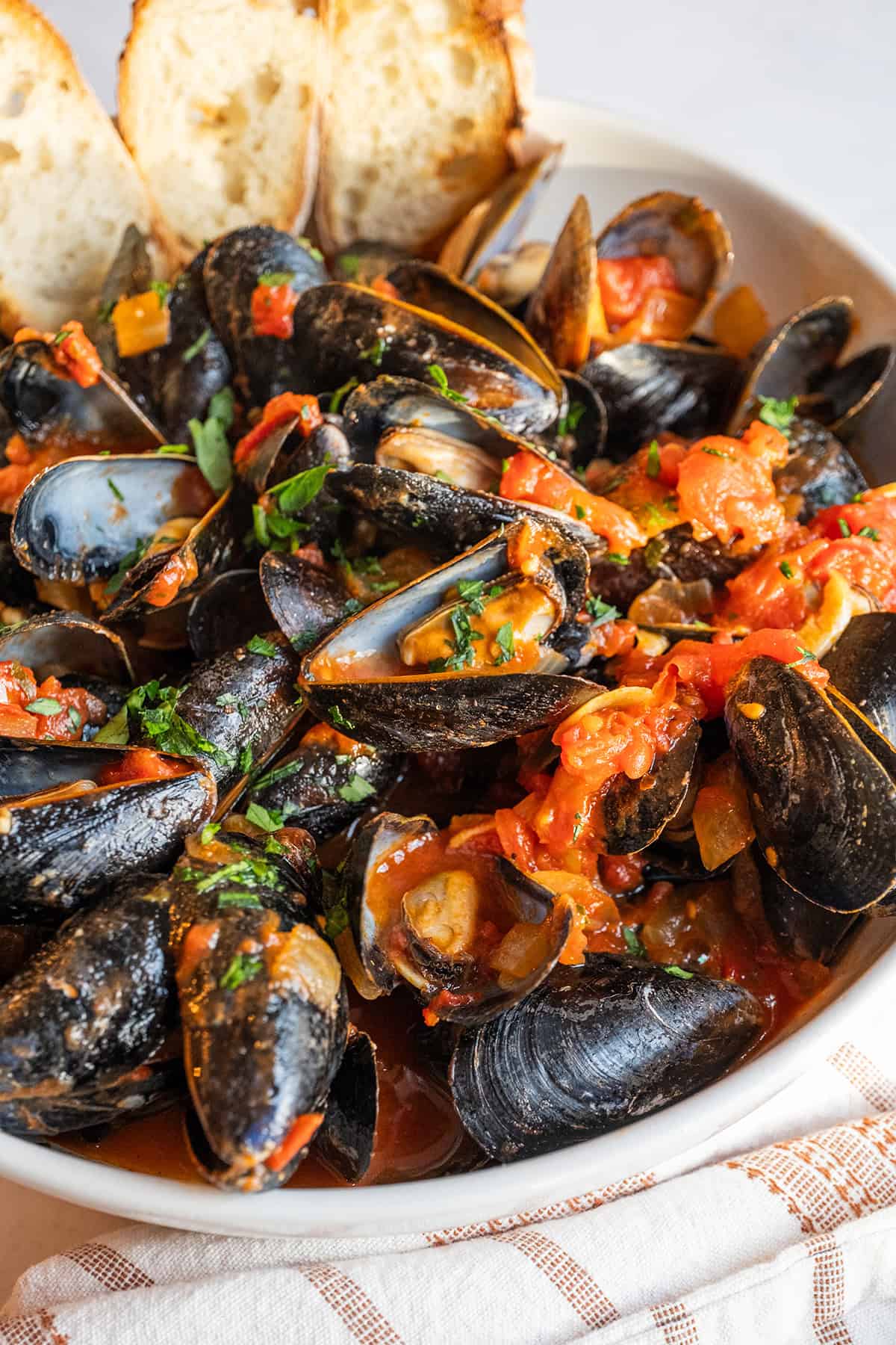 Mussels Fra Diavolo in a serving bowl with crostini.