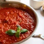 Marinara sauce in a pan garnished with basil.