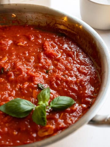 Marinara sauce in a pan garnished with basil.