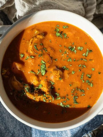 Butter chicken soup in a bowl topped with cilantro.