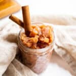 Spiced apple chutney in a mason jar garnished with cinnamon sticks.