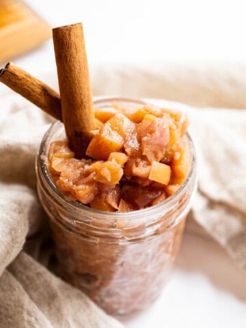 Spiced apple chutney in a mason jar garnished with cinnamon sticks.