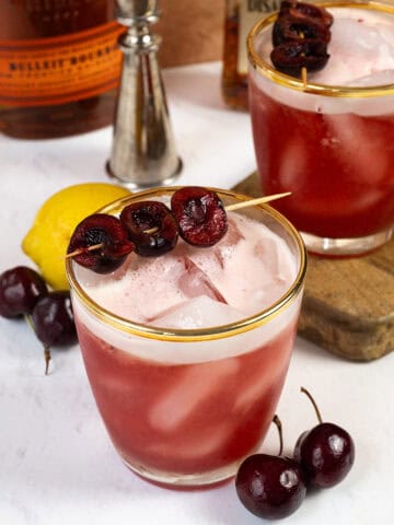 Cherry amaretto sour in a glass with a cherry garnish.