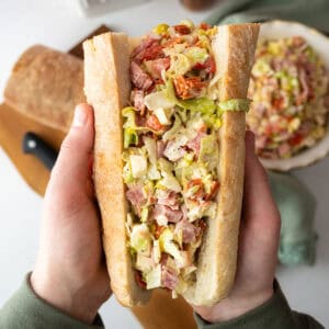 Chopped Italian Salad in an Italian sub held by two hands.