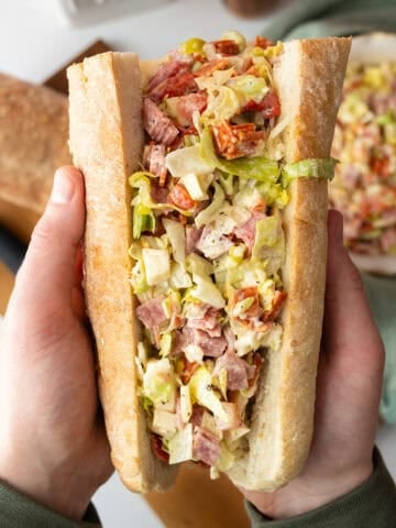 Chopped Italian Salad in an Italian sub held by two hands.