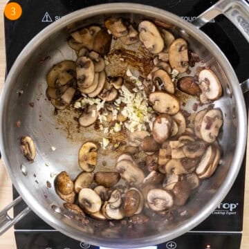 Sauteed mushrooms with garlic added in pan.