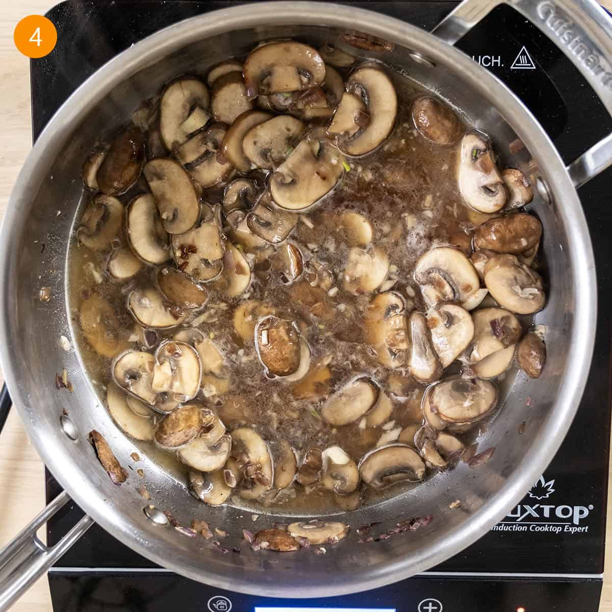 Velvety Garlic Mushroom Pasta 7 Simmering white wine with mushrooms in pan.