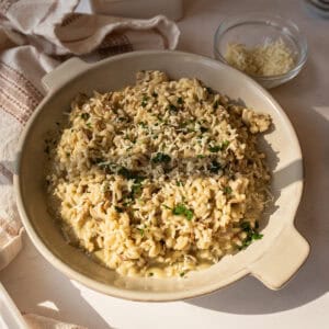 A bowl of risotto with mushrooms topped with extra gorgonzola and parsley.
