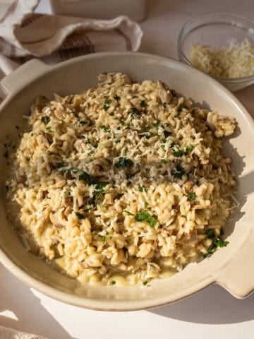 A bowl of risotto with mushrooms topped with extra gorgonzola and parsley.