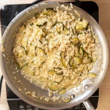 Zucchini with creamy and runny texture in saucepan with parmesan combined.