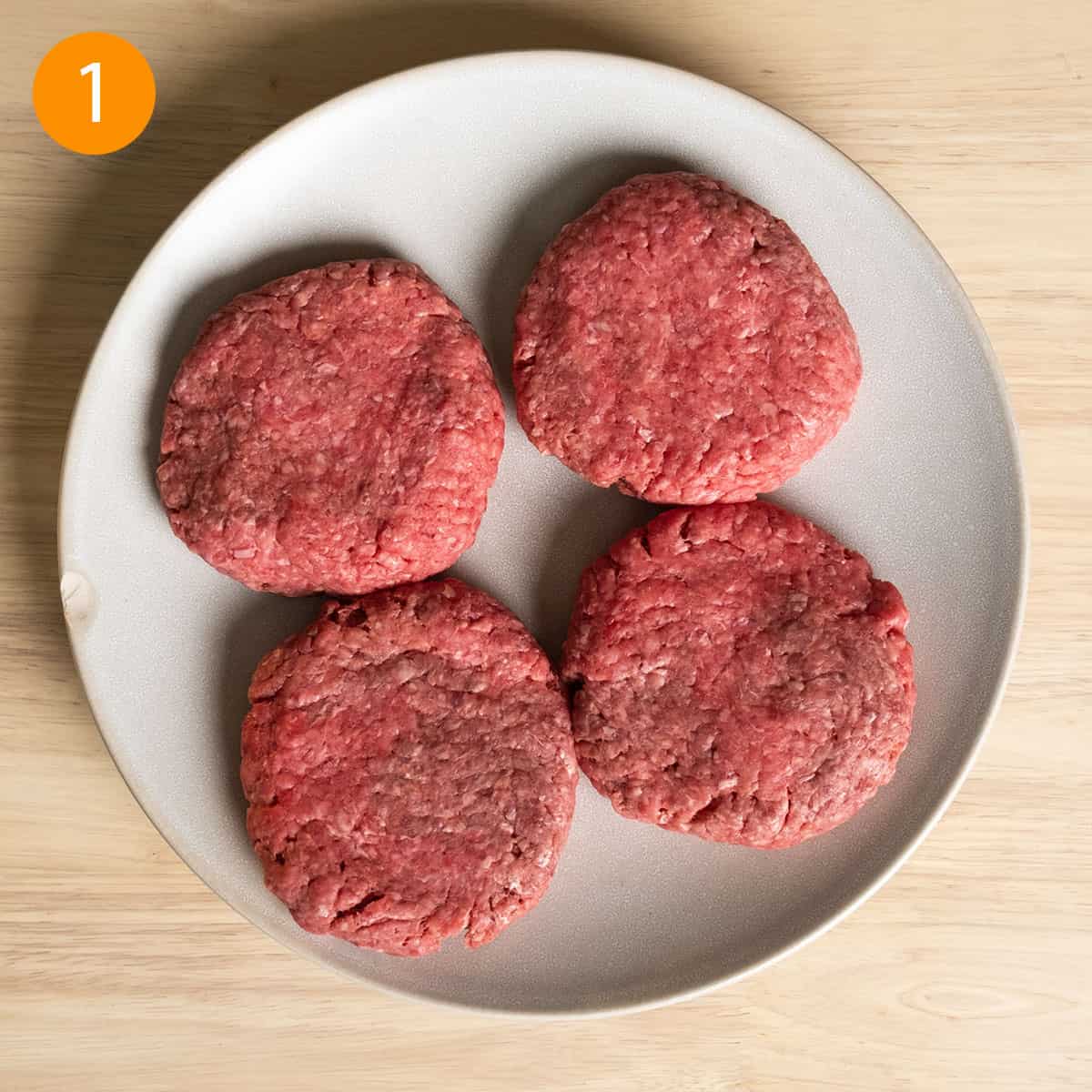 4 burger patties prepared on a plate. 